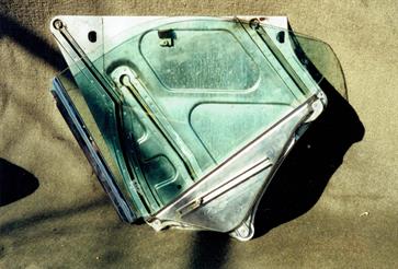 Rear quarter window out of the car and in the down position.  Mechanism is rather complex and this photo shows the mounting plate with tracks for the window to follow.  This item took the Jaguar engineers many months to develop and delayed the release of the XJC.   All this, plus the electric motor and lifting mechanism, had to be manipulated inside the quarter panel, bolted in place and adjusted.  A long, drawn out and frustrating process.
